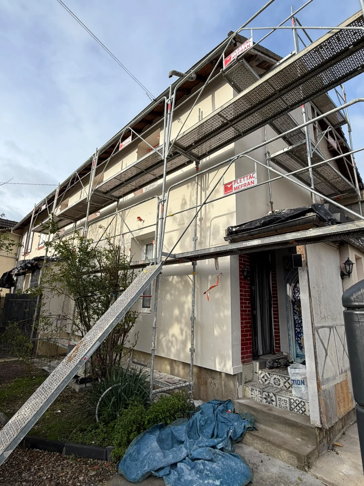 Pendant — ITE à Mantes-la-Jolie : Façades en cours de travaux, avec protections et échafaudage.